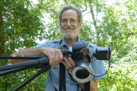 Ron Goor ’62 holding a camera with a butterfly resting on it